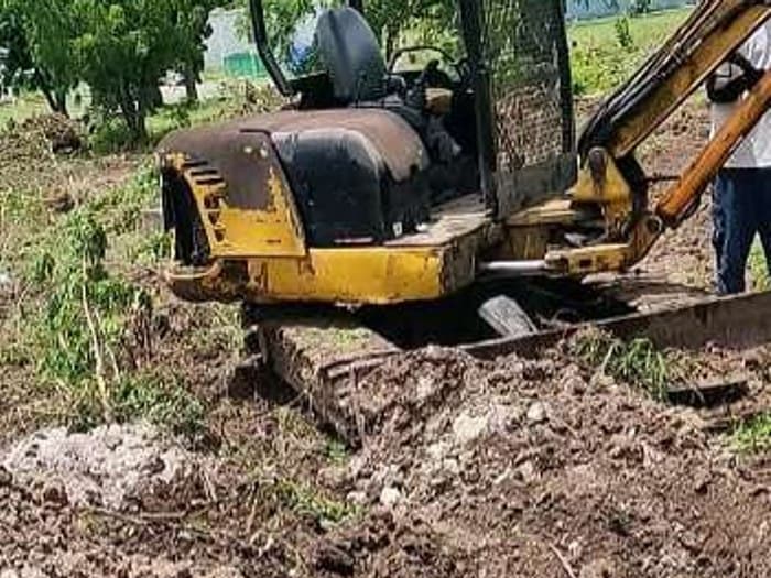 Mini excavator digging a test pit for the Courts Unicomer investigation